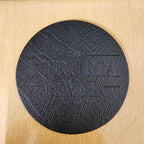 Black round coaster with embossed text