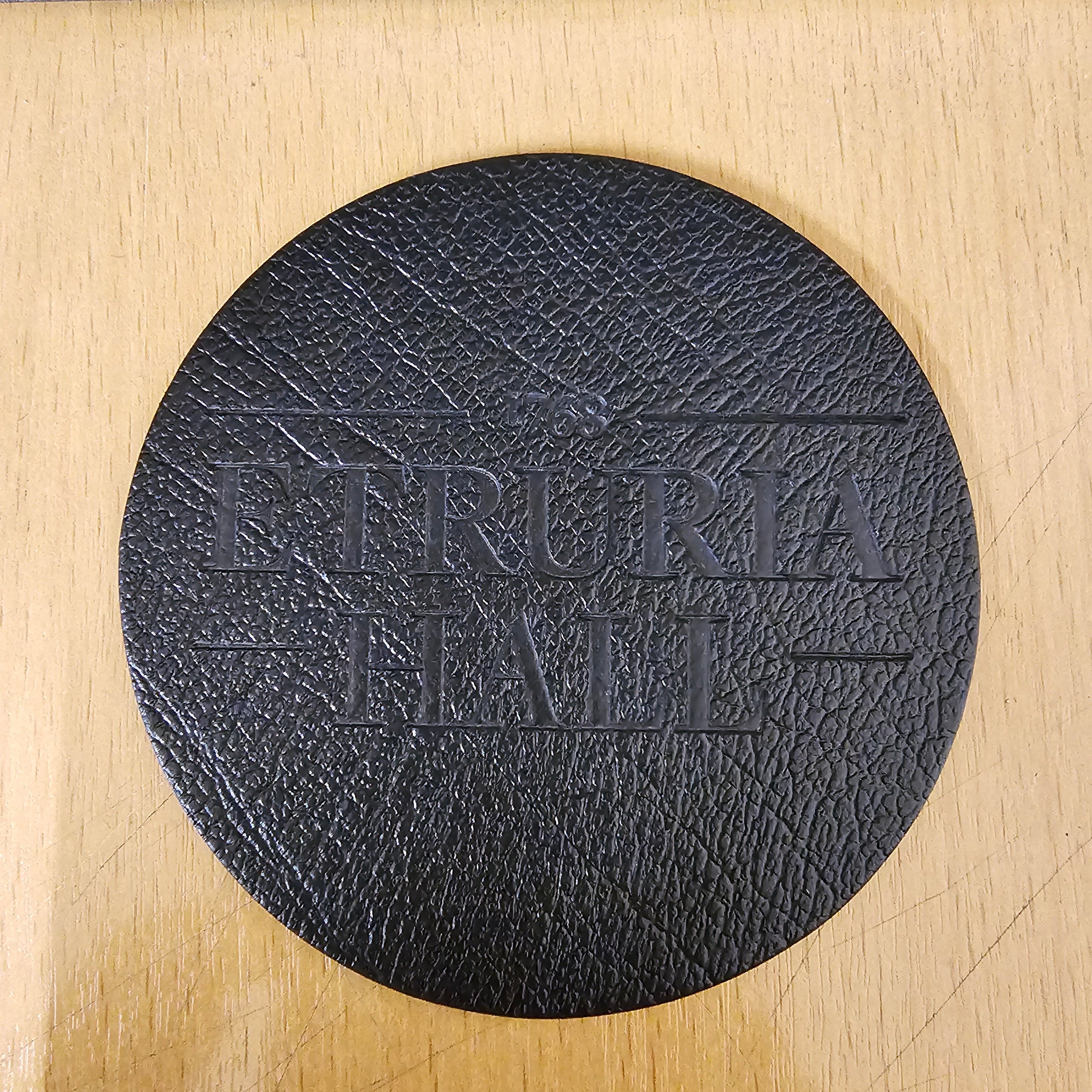 Black round coaster with embossed text